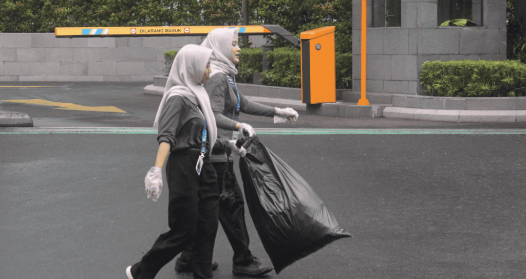 Terlihat dua mahasiswi penerima Beasiswa KSE UIN Jakarta sedang bersama-sama membawa kantong hitam berisikan sampah pada pelaksanaan GPSN 2025