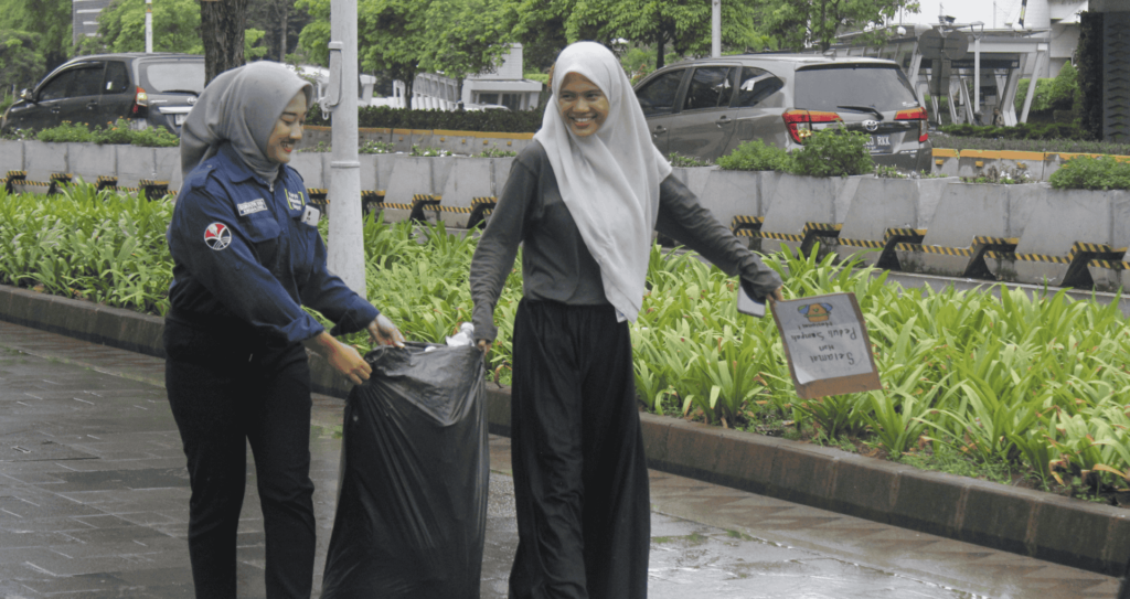 Potret keseruan Edgin, beswan KSE UPI, yang terlihat sedang membawa kantong hitam berisi sampah hasil GPSN 2025 bersama salah-satu beswan KSE UIN Jakarta